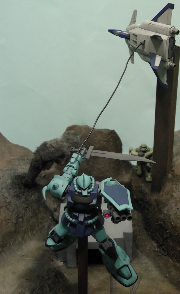 ノリス・パッカード大佐の駆るグフカスタムの初登場シーンです。敵方のジェットコアブースターにヒートワイヤーでぶら下がり、35㎜マシンガンの斉射をします。グフカスタムはHGUCです。