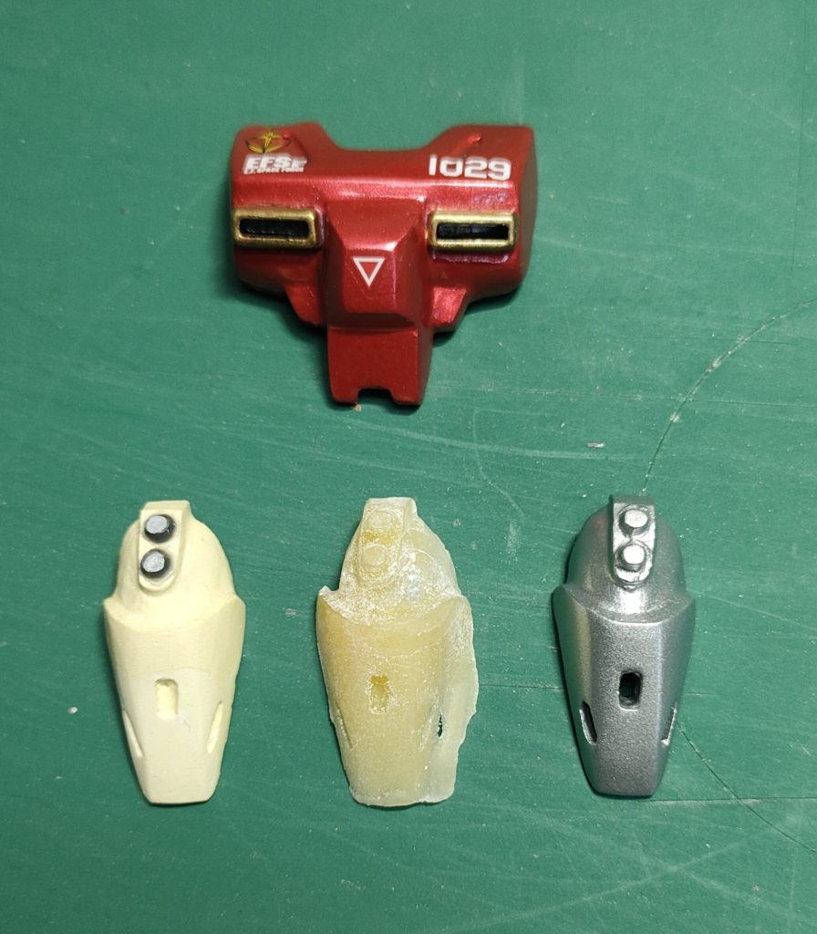胸の方の原型は壊れてしまったけど、足の方があったので、説明しますと、仮組したパーツにワセリンを塗ってから石膏を盛り付けて固まったらデザインナイフやヤスリで形を作ります。左側が石膏の原型で黒のは何かのパーツを瞬着でつけてます。それをおゆぷらで型取りして、タミヤの光硬化パテでパーツ化します。真ん中は失敗作ですが、上手く複製出来たらヤスリがけなどできれいに仕上げます。胸のパーツの金色の部分はあとから何かのパーツを後付けしたものです。固定は小さなネオジム磁石を使っています