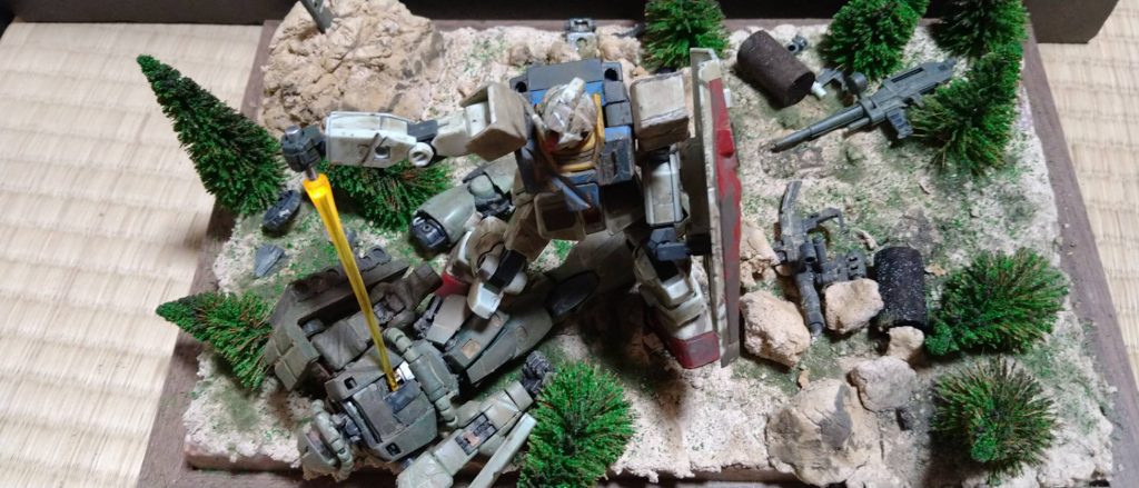 上から見た写真です。ジャンクパーツ等散らかし、破壊された機械、武器を表しました。木が倒れまくっているのがわかります。ビームサーベルはLEDを仕込み光らせました。上から見るとザクの様子がわかりやすいです。燃えた木も再現しました。 