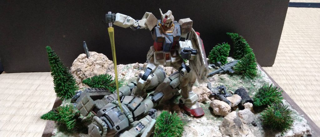 全体的にはタミヤのウェザリング マスターを使い、金属や刷り、デザインナイフで削りました。岩は、ゴムで粘土をきって制作しました。ガンダムがとどめをさしているようにしています。