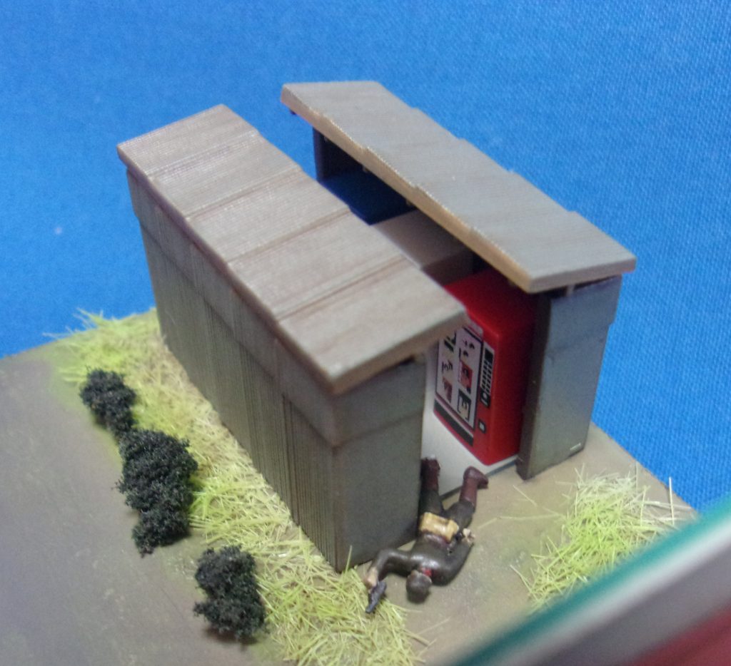 斃されたジオン兵B。トタン張りの目隠し小屋の中には成人向け雑誌やビデオの自販機が並んでいます。