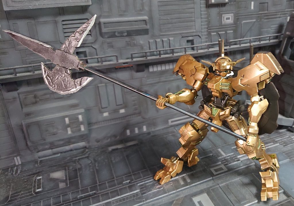 ハルバードをメイン武器　背中のショーテルをサブ武器に戦う対MA用ガンダムフレーム　黄金の装甲とメタルグリーンの刺し色 