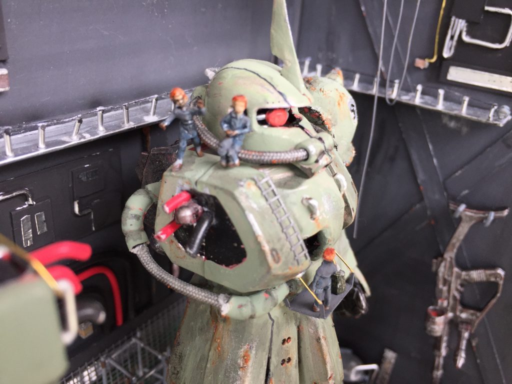 オーライ！オーライ！新しいザクの腕を慎重に取り付ける作業者たちをジオラマ化しました。