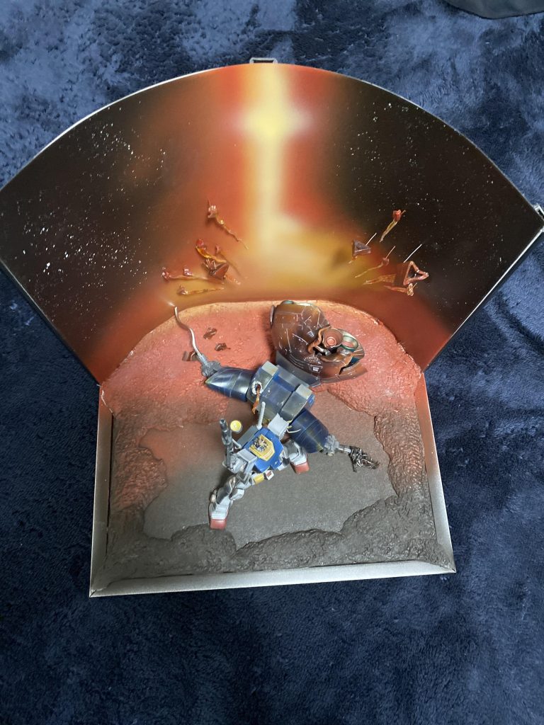 上からだとこんな感じです。背景はキットの位置を見ながら、エアブラシで描いています。地面は石灰粘土を貼り付けて背景の赤から黒になるように塗りました。