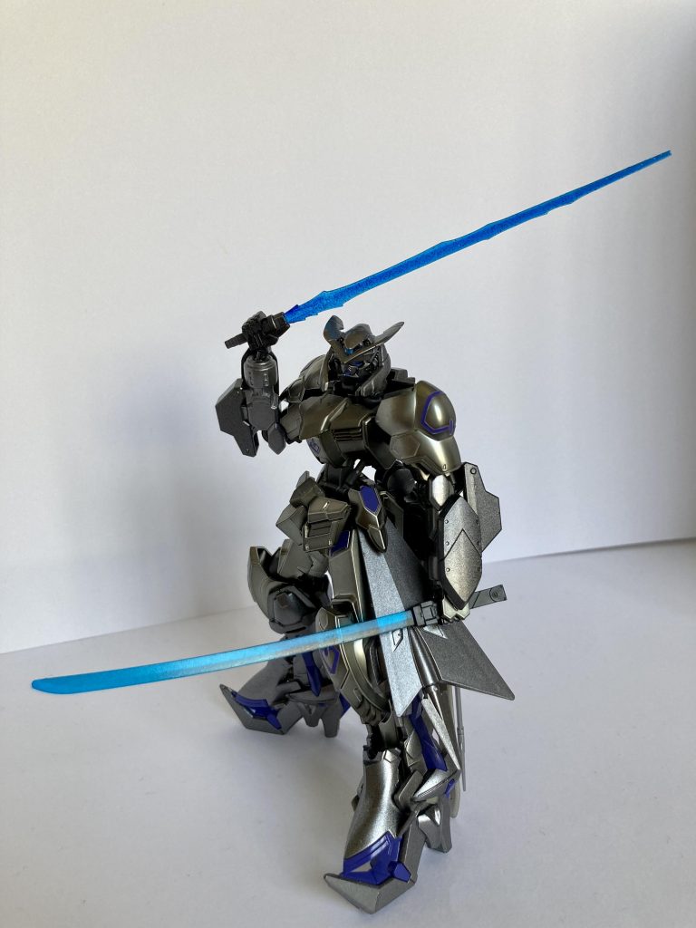 ・エイハブパーティクルブレード×２　通常ナノラミネートアーマーは、ビーム兵器に対して高い優位性をもつため、ビーム兵器は、有効な攻撃手段とならない。しかし、この兵器の刃は、通常ビーム兵器とは異なり、エイハブ粒子により構成されているため、ナノラミネートアーマーを無効化し、敵機を簡単に融解・切断することができる。   欠点は、エイハブ粒子を肉眼で明確に観測できるほど高密度に凝縮する必要があるため、粒子消費量が著しいことである。この兵器を使い続けるとMS本体の強度にも影響を与えてしまう。最強の刃であるが、同時に自らをも危険にさらす「諸刃の剣」なのである。　対MA用の調整では、太刀型だけでなく、新たに騎兵長剣（コンツェシュ）型のものが追加されている。