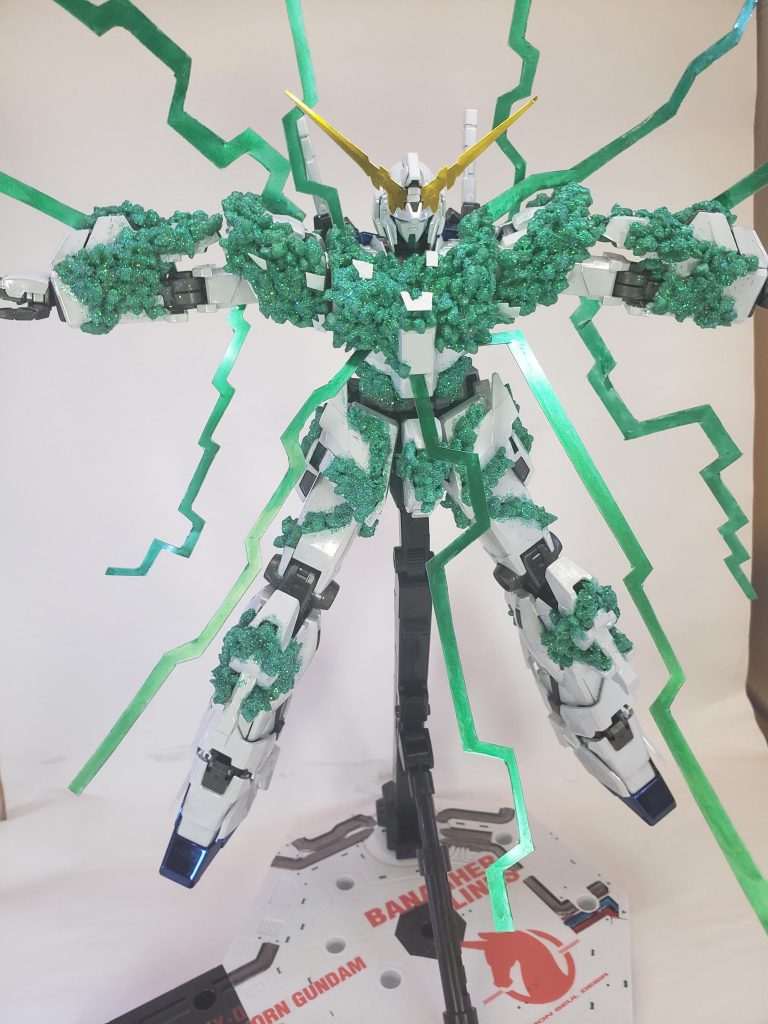 100均にて購入したインテリアカラーストーンをガンダムマーカーEXのルミナスグリーンで塗装し、一粒一粒細かいながらも接着しその上からグリーンのラメパウダーを接着剤を塗った上からふりかけ結晶体のキラキラ感を表現。透明のプラバンを使用し、帯状の物も表現しました。