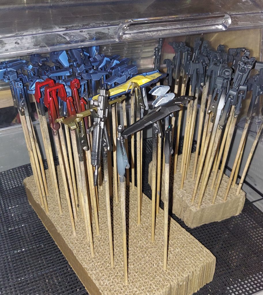 黒サフの上から全てのパーツに塗装が完了した状態です。赤色は水性ホビーカラーのメタリックレッド、白のパーツは雲母堂MGパールを混ぜたクリアー、シールドのパーツは水性ホビーカラーのゴールド、関節フレームは水性ガンダムカラーのティターンズブルー1、ライフル等はタミヤアクリルのガンメタルを使用。頭部カメラ部には水性ホビーカラーのメタリックグリーンを塗装後、ガイアエナメルの蛍光グリーンを乗せてUVライトにて発光するようにしています。