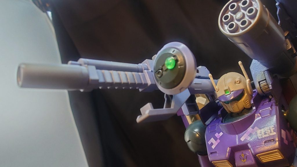 本来なら「捨て石」とも言える最初期型の実践投入に当たっては、逆にこれを好機と捉えた技術開発部によって開発中の新兵器が装備されることとなった。右肩には従来の火薬式低反動キャノン砲に代わり、電磁加速砲、いわゆる「レール・キャノン」が実装された。後述するビーム攪乱幕が使用され、ビーム兵器の使用が制限される状況下において、従来の火薬式を大きく上回る高速・長射程の弾丸を射出する本装備は、技術的な問題から装弾数や駆動時間に制約があるものの、対艦・要塞攻略において大いに戦果が期待された。