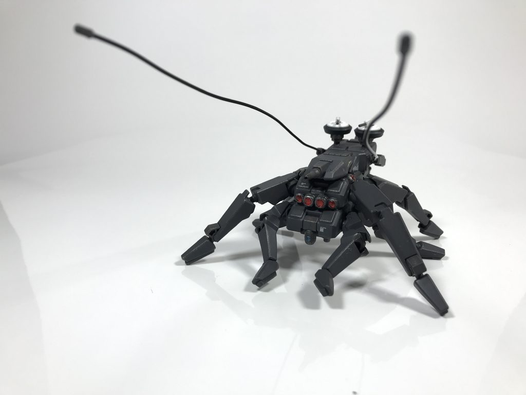 [ハエトリグモ型支援機:SA-001アダンソン]ジムスナイパーK9のドックパックをベースに製作された本機専用の支援機。ハエトリグモをモチーフとしており、どこかコミカルな動きが特徴。背部にはクローアンカーガンが搭載されており、地形に食い込ませての高速移動や敵機に打ち込んでの移動阻害など、多彩な行動を可能としている。その見た目の裏腹に、機動力は高く、森林やデブリ地帯など、視界の悪い環境において、サルティシディア本体との連携は脅威となる。なお、アダンソンという個体名はアダンソンハエトリというハエトリグモの一種の名前が由来である。