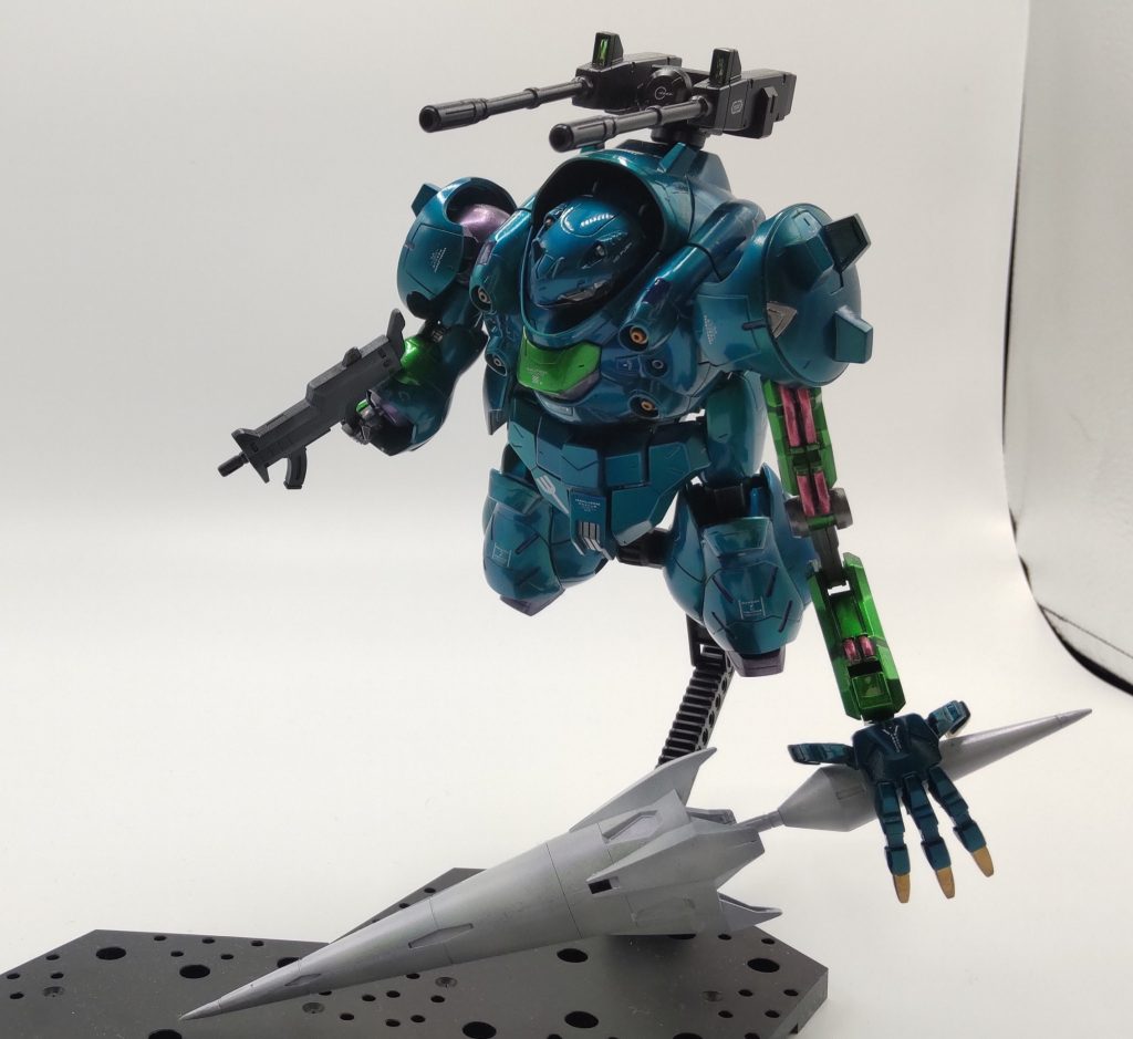 【マイ設定】厄災戦末期開発されたガンダムフレームの１機となる。当機は、他のガンダムフレームや一般MSと連携してMAを撃破する事を目的とした特化機（超重装甲＋大型武器での吶喊機）として開発された。　MAとの戦闘時、随伴するプルーマ群を排除または、搔い潜らなければMAに接敵できず、無限に増殖するプルーマ群相手に、当時の戦力では中々有効な戦術が打てないでいた。　そんな中、ASW-G-1ガンダムバエルは単騎でプルーマ群を掻い潜りＭＡを撃破する事に成功している。当機はバエルの戦術を役割毎に分散させ一般的な戦術に落とし込める様な仕様としている。　仕様としては、下記となる。①装甲強化：プルーマ群を掻い潜りMAに近接する為、多少の被弾をモノともしない超重装甲にエイハブウェーブの干渉を強化し、ナノラミネート装甲の強度を増す仕様とした。使用時表面装甲が鏡面状に輝く点が特徴として挙げられる。当機能は強力なエイハブウェーブを必要とし、塗料の劣化が激しい（一回の戦闘毎に塗料の全塗装が必要）ことから、2基のエイハブウェーブ積んだガンダムフレームのみ使用可能な機能となる。ただ使用時他の出力を犠牲にし、かつ塗料の塗直し等のデメリットから、ガンダムフレーム機であっても基本的に使用する事は稀となっている。②索敵・弾幕能力を強化する為、バックパックにパッシブセンサー付きの２連装キャノンを実装。③直線的な速度を増す為バックパック及び脚部のスラスターの強化④MA接敵時少しでもダメージを増すための大型ランス⑤ランスを保持、激突時の衝撃に耐えられるよう、左腕部のフレームを大型化。⑤合わせて、大型の左腕部に希少金属製ネイルを実装、左手のリーチを少しでも延長できるよう、多関節化を実施している。※右腕は汎用性を維持するよう標準的な腕部とした。上記のような仕様により、敵プルーマ群を掻い潜りMAに接敵・損害を与え足止めを行い、後詰の格闘戦機能を強化したガンダムフレームによるMAの撃破を目指した機体となる。　戦術としては有効であると判断され数度の実戦を経験したが、機体コンセプト上どうしても危険性が高く、最終的には敵MAによる狙撃により撃墜・乱戦の中機体喪失の結果となった。