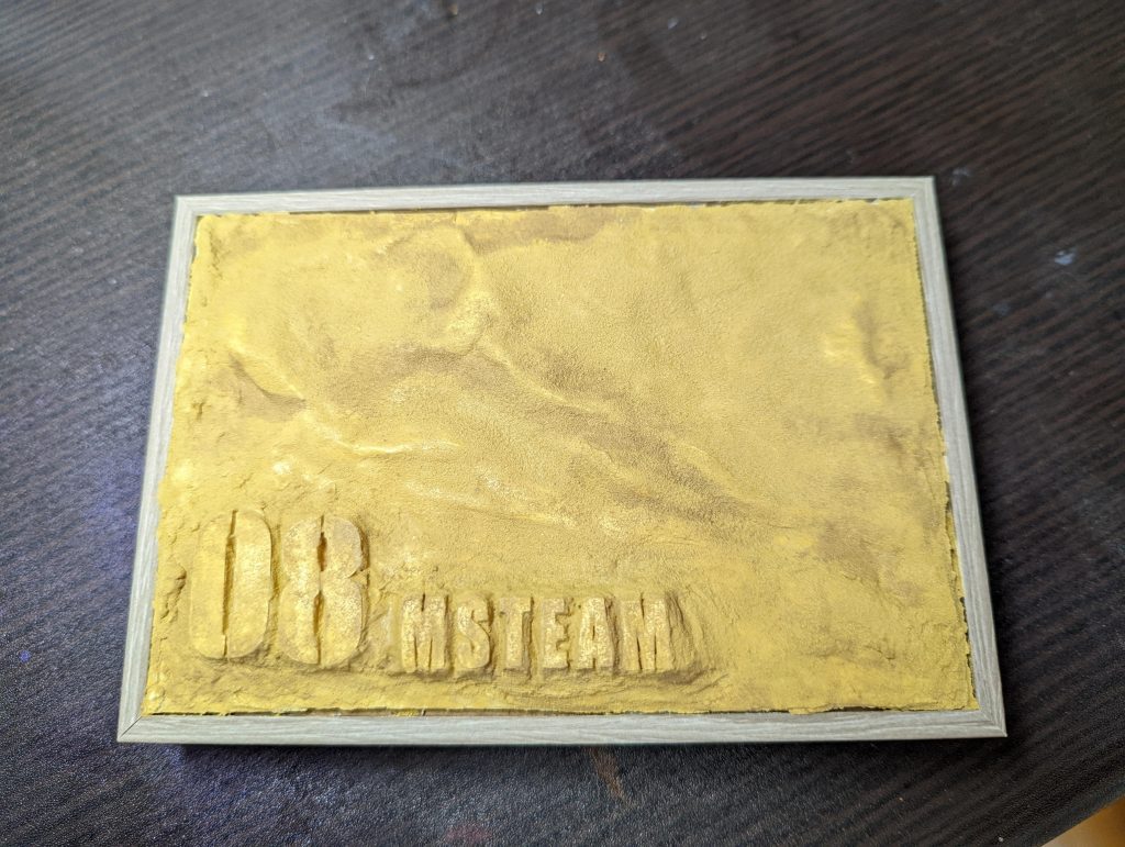 台座はこんな感じにささっと。100均の小さな木箱の小物入れを裏側にして、同じく100均のクラフト用粘土を引き詰め、乾燥後外して、木工用ボンドで接着しています。文字は、プロッターで切り出した0.1mmプラ板、粘土を盛りその上に文字を置き、隙間は木工用ボンドで薄めた粘土をパテ代わりに使って整えています。色はタミヤのテクスチャペインライトサンド。100均の大き目の筆を使い捨てにして塗りました。乾燥後にタミヤウェザリングマスターで、色ムラを整え終了です。