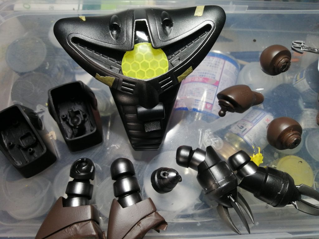 モノアイは切り抜いて100均のプラスチックの大きなボタンに、反射テープを貼って作成首はどうするか悩んだ結果、同じく100均のおまけの入っているタマゴ型カプセルに細く切ったプラバンを角度をつけて接着隙間を瞬間接着時で埋めて蛇腹状にしていますモノアイの中は移動レールらしきものを作り、お弁当のフタの透明プラを切り抜いてカバーを付けています足首はボールジョイントを増設して隙間カバーを作成曲げたときに中身が見えないようにしています