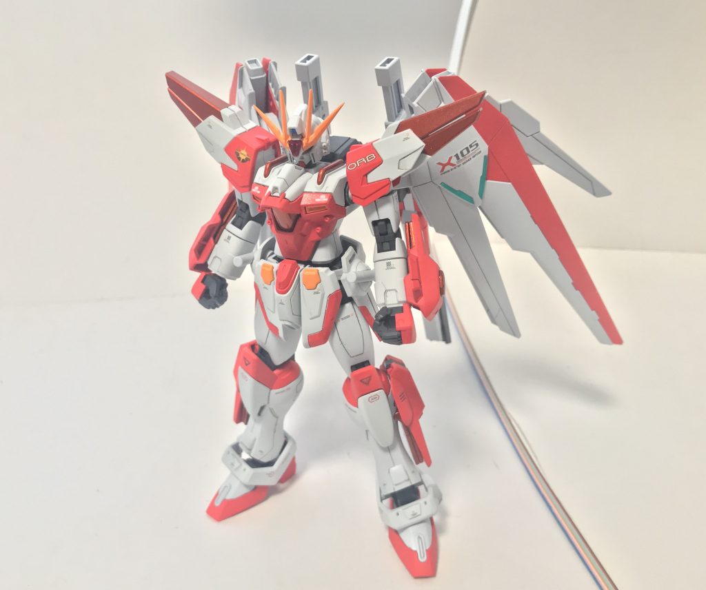 正面。各部に配置されているメタリックオレンジのパーツはウイングガンダムゼロ炎を参考にした「炎クリスタル」に近い産物であり、追加エネルギー源として機能しているほか、炎クリスタルそのものの共鳴によってバーニングバーストの更なる力を引き出すことに成功している。余談ではあるが、前世代機のストライクスフィーダでは所属マークが地球連合だったが、ソルストライクトライにおいてはフリーダムのパーツを取り入れたためにオーブ軍所属のものに変更されている。