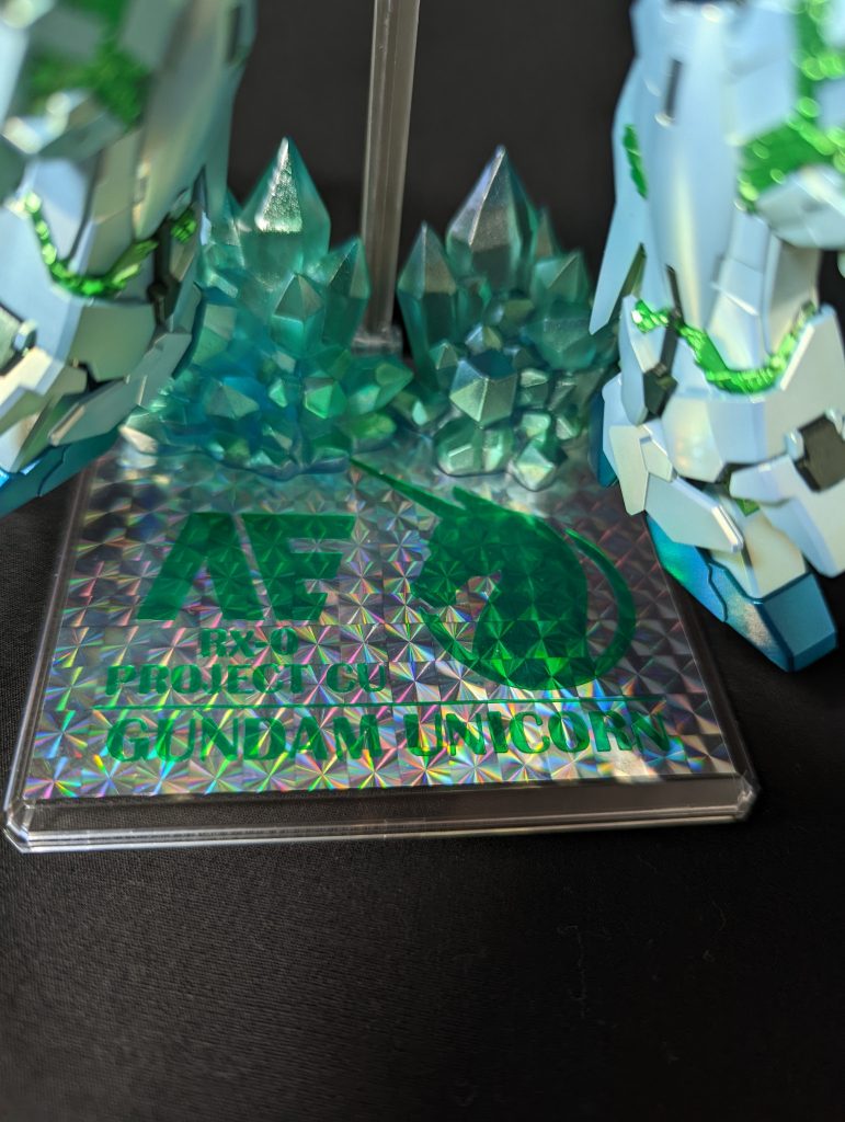 台座はヨドバシ様等でも売っていますごくごくありふれた汎用性の物に、ホログラムのカッティングシートを貼り、ユニコーンのロゴや文字は、ローランド様のプロッターでクリアーグリーンのカッティングシートに切り出して上から貼り付けました。結晶体はセリアで売っていた物に、本体の結晶体と同様の塗装レシピを下部に行い、上部は薄っすらクリアーグリーンを塗装しています