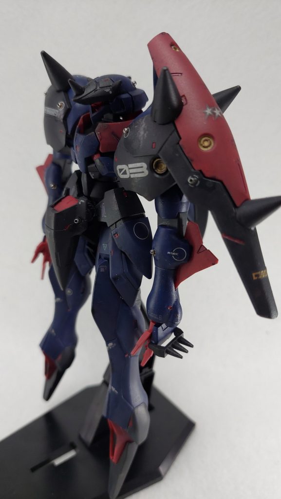 レッドポイントに見立てられそうな部分は面相筆や先を潰したつまようじでちょんちょんと塗装。またGNバルカンや各部の小さなポチポチした部分にはカシメ玉を接着して金属っぽさを追加しています。デカールは前回多用したオレンジ系は封印し、ホワイトに加えてパステルバイオレットや同ミントを貼り付けてカラフルさを演出しました(ウェザリングでだいぶ色が立たなくなってますが)今回はサーフェイサーもラッカースプレーではなく水性のものを筆塗りしたのですが、合わせ目消しした後などにマスキングせず塗装できるのが便利ですね。一方で逆に筆塗りできないような奥まった場所は塗装できないので、これはこれで計画性が必要なのも分かりました。可能性が広げられそうです。