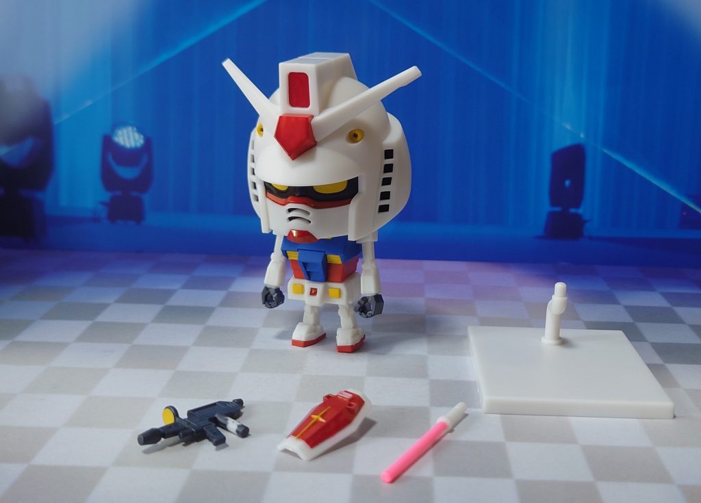 ガンプラくんと付属品。ビームライフル、ビームサーベル、シールドの基本セットに加え、展示ベース付き。