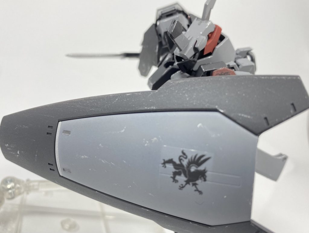 [肩部大型シールド、短刀]本機の右肩には、大型のシールドが装備されている。大型艦艇に用いられる装甲板を加工し、ナノラミネートコートを施したもので、相応に重量があるものの並みのMSの装甲とは比べ物にならない硬度を誇っている。また、右腰部には短刀が装備されている。刃渡りの短いこの武装は取り回しが良く、懐に入り込んでくるような素早い相手などに対応しやすい武装である。  