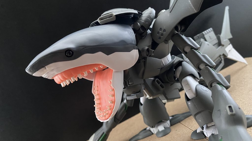 　戦前は造船所だったこの基地は、すぐ隣にビーチがあり多くの人々が涼を求めている。戦時中にもかかわらず。いや、戦時中だからこそなのだろうか。　そんな基地のMSハンガーの奥。ひっそりと屹立するそのMSを見た我々は…。暑さで頭がやられたのかと…。XMSM-03S シャークゴッグ　名は体を表すと言うが。この機体はツィマット社のゴッグ、その後継機として総合整備計画に基づくMSの試作機を使用して開発された。ASLM社(聞いたことのない社名だ…)によって改修されている。　ここに、ASLM社の技術者たちの会話を記録した映像がある。二人の技術者がモニターに映る映像を観ながら会話をしている。モニターはこちらに背を向けているのでどのような映像なのかはわからない。「技術長これは、」「見たまえ、地球の大部分は海だ。この地球の制圧には、この海の制圧が重要だ。その為にこの海の最強を知る必要がある。」「はぁ…最強ですか、」「そうだ、そして、その最強がこれだ。…サメだよ。」「サメ…ですか？」「この資料映像を見てみたまえ。」「…こ、これは、お、大きい、空母より！」「これもみたまえ…。」「そんな、サメが地中を！…ああっ！竜巻に乗って空を飛んでっ！う、宇宙空間にまで…」「そうだ。サメとは素晴らしいのだよ。…そして、これだ。」「あ、頭が二つ、三、四、六つもあるのですか？」「フフフ…どうかね。」