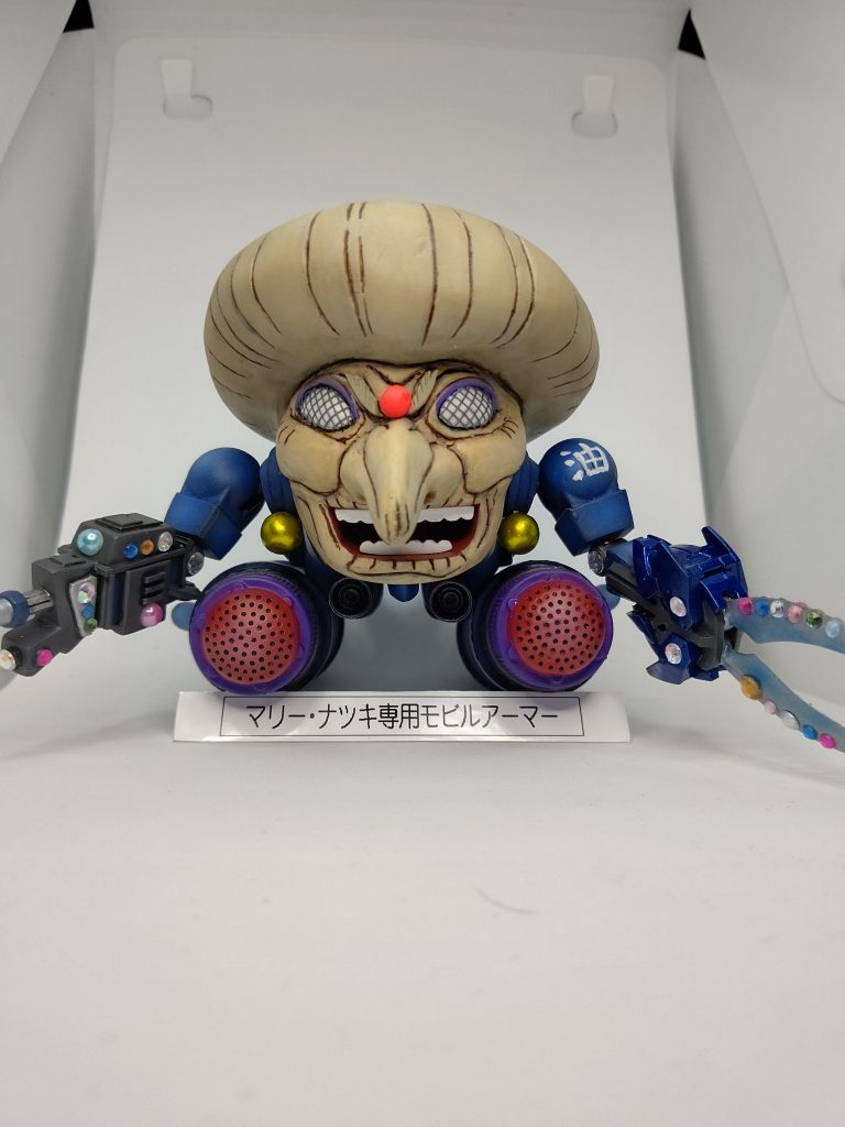 カラーリングはザクレロの黄色にしようか悩みましたが、顔の肌色と被ってしまうため湯婆婆の服の青にしました。耳飾りは戦艦グワジンのエネルギータンクをキャンディー塗装にして取り付け。湯婆婆の指輪をイメージして腕の武装にキラキラデコシールを貼りました。