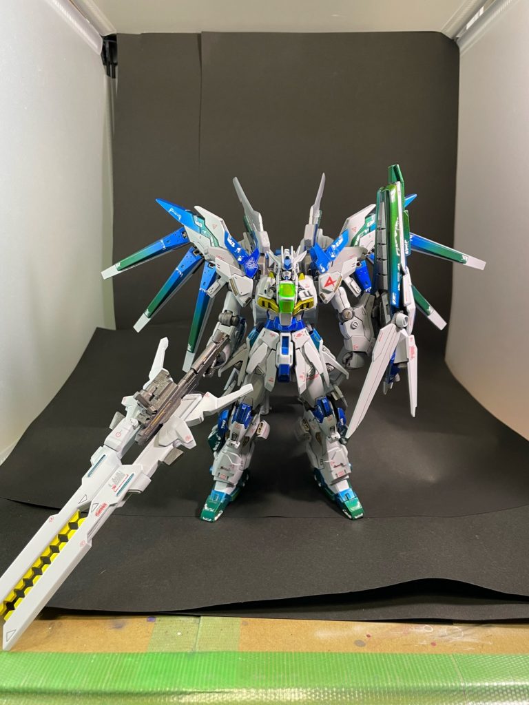 シールド・ライフルを装備。シールドはHi-νガンダムブレイヴのものを基礎に、シナンジュスタイン、EG νガンダム、ユニコーンのシールドをバラして再構成。そこにガンダムダブルエックスのリフレクターパネルの一部を加えてνガンダムHWSのシールドを彷彿とさせる外観に。先端にはビーム砲、後端にはブースターが3基配置されており、武器にもなり姿勢制御や推進補助も可能な万能盾という設定。ライフルはグリップ基部周りをHi-νガンダム、砲身をガンダムダブルエックスのツインサテライトキャノンを2門合体させています。長距離射撃時には可変し、構え方も変わります(後述参照)。