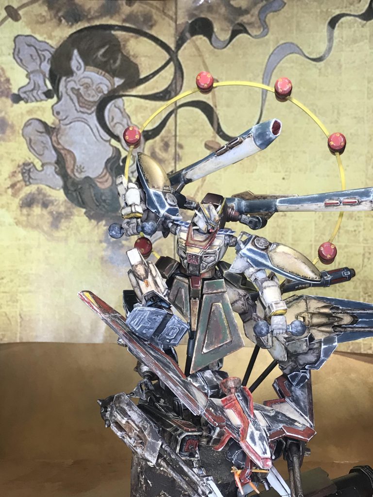 元絵と並べて前掛けそのままの大きさだとシックリこなかったので左側の前掛けだけプラ板で大きいものをつくりました。太鼓のバチ元絵が両手に太鼓のバチを持っているのでビームサーベルの柄と丸い部分はグワジンのプロペラントタンクから製作しました。