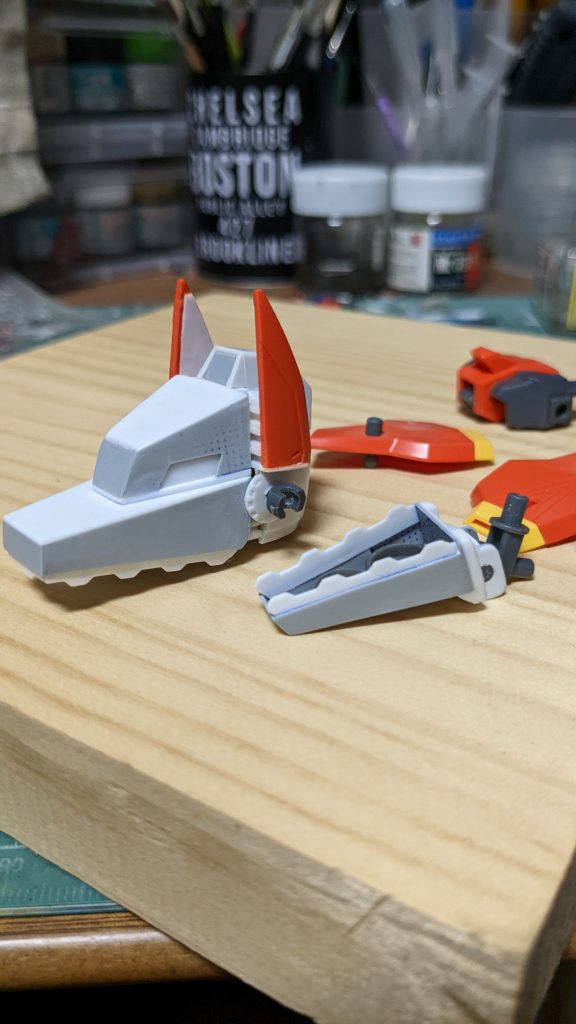 最初に取り掛かったのはウルフ形態の頭部です。CSジムヘッドの後頭部にパーツを取り付ける形で制作しました。歯の白いジグザグ部分はディティールパンチで型を抜いたプラバン。顔前面と下あごはマス目付きのプラバンで制作したものです。オレンジのパーツはジャンク品で買ったガイアガンダムのパーツです。