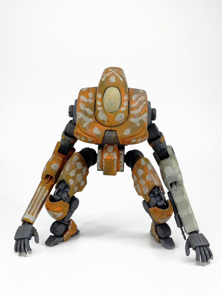 設定的なのオヤブンはヨツバ重機を代表する機種であり皇国の工事現場でもっとも数多く見る事のできる民生用WTである。操作性に優れとにかく頑丈。年式の古いオヤブンは性能こそ近年の機体には及ばないものの構造のシンプルさからもはや錆の塊にしか見えないような機体ですら動かす分には大体動くと言われるほどの耐久性を誇り十分な整備環境を整えられない途上国では９０年式までの機体をあえて求める需要があるほどである。特にコクピット周りは危険な現場での作業に備え厚い鋼板で覆われており小銃弾程度であれば貫通不可能なほどの頑強さを持つ。そんなオヤブンだがその需要故に工事現場から盗難され、海外密輸市場に流される事例は枚挙に暇無くこの機体も３０年前に皇国で盗難された記録が残っている個体であった。盗難後２５年ほどは旧央国圏で使用されていたらしく発見されたブルースランドのとある集落には5年ほど前に流れ着いたようである。集落で資金を出し合って購入された本機は彼らにとって貴重な重機であり電源装置であり、そして他の集落からの襲撃に対抗するための防衛戦力である。元の塗装は剥がれ傷まみれではあるが部族の伝統的な呪術紋が描かれフレームには錆も無い良好な状態が保たれており、盗まれた挙句の果てとしては極めて幸運な機体であると言えるだろう。