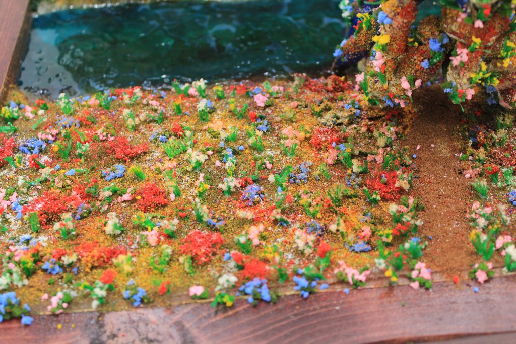 地面は紙粘土ベースに塗装を施し、カラーパウダーで土と草を作りました。花はジオラマ用パーツです。