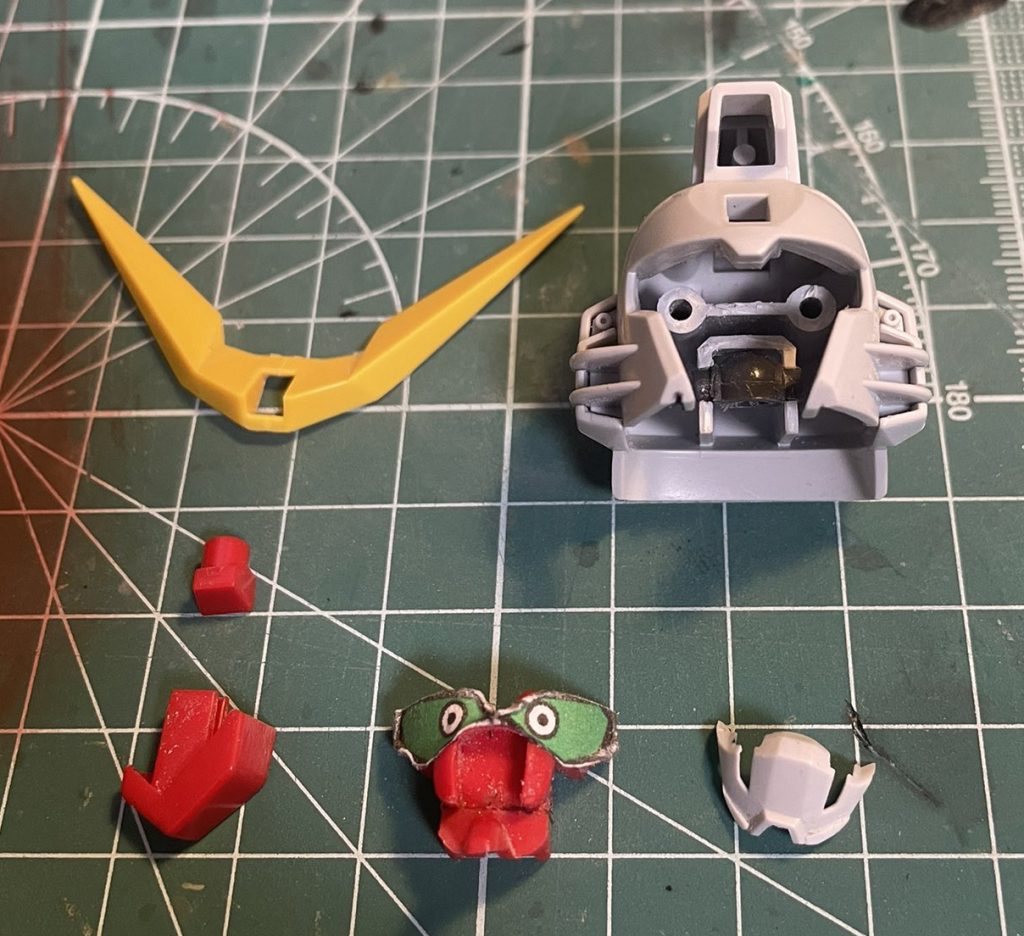 ◆メインとなった顔の加工詳細内部の赤いパーツはクマドリ部分をすべて削り取り平面に、メインカメラと瞳の部分をつないでいる個所を切り取ることでメインカメラとフェイスそれぞれを後ハメできるように。マスクもデフォだとメットと一体成型なのでノコで切り離しています。さらに顎の下側を2mmほど削り小顔化、それに伴い顎下のラインはプラ板で作り直し、メット内部のダボがハマる位置とポリキャップの受け口を奥側に削り、フェイスを2ミリほど奥にずらせるようにしました。メットも頬あてが長いので先端を2~3mm短くしています。