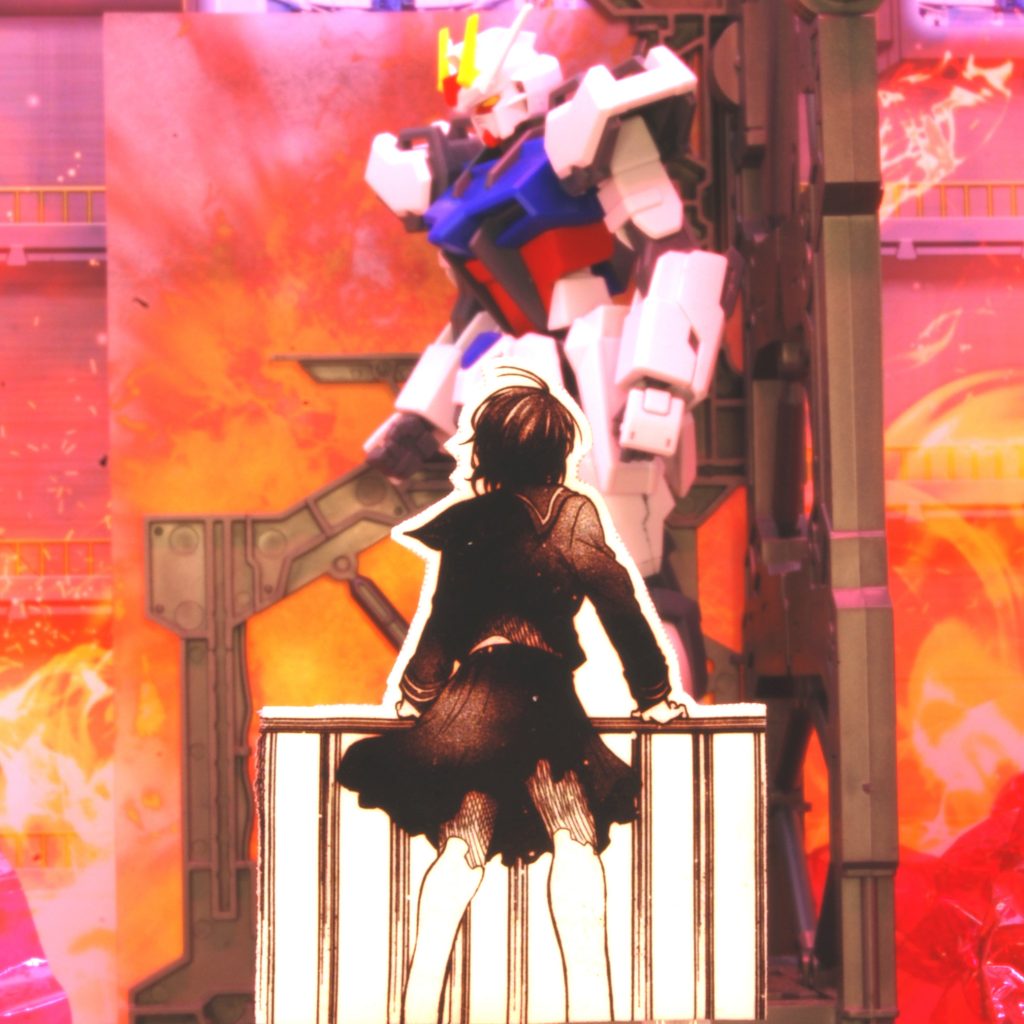 　撮影の全体像はこんな感じです。前回の投稿でストライクガンダムの格納庫を焼いたのは今回の試作も兼ねたのですが、背景紙も取り替えるなどして気合い入れたもののほとんど影響なかったような…。　背景の爆発エフェクトは、半透明のプラ板に無料画像素材から引っ張ってきたものをプリンタで出力。透け感はともかくトリミングすると煙たい感じになってくれたので、煙表現のために買ってきた綿や塗料が丸々無駄になりました（笑）。　ＳＥＥＤ本編準拠だとここはディアクティブモードでないとおかしいんでしょうけど、このシーンはエールストライクガンダムをあえて中途で完成させた直後の心象表現なのでこれで正解です（ＨＤリマスターのキービジュアルもこんな感じですし）。