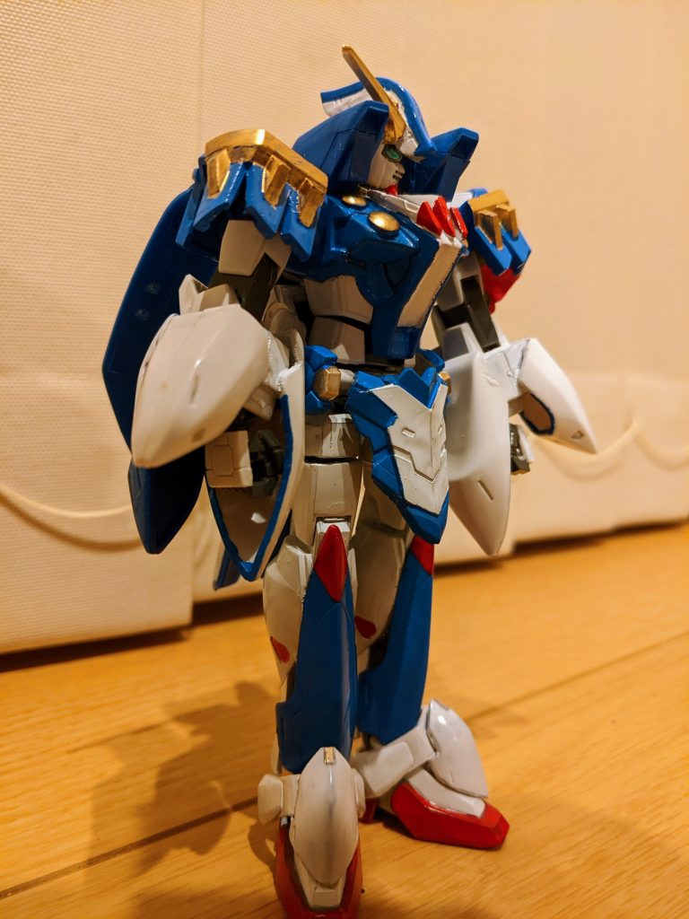 ベースはＨＧ１／１４４のＯガンダム。そこに１／１４４ガンダムローズのパーツや何かのジャンクパーツ色々を組み替えて張り付けていきました。頭部はガンダムローズの帽子をカットして前角度に変えて、アンテナパーツを半分にしたものを両サイドに接着しただけです。これだけでヴェルサイユっぽくなる不思議(笑)体はＯガンダムそのまま、襟にローズのコアランダーのバーニアを、胸にＯガンダムの襟アンテナ２本と、それっぽいアンテナ、クリアのポイントパーツをつけて塗装しました。腰部はＨＧ１／１４４ダブルオークアンタで、腰前とサイドはＵＬＴＲＡＭＡＮの余剰パーツです。前腕の袖はＨＧ１／１００ウイングゼロカスタムの肩アーマーの白い部分です。足もＯガンダムをベースに、スネ当ては１／１００デスサイズヘルカスタムの腰サイドアーマー、足首のは１／１００ウイングゼロカスタムの腰サイドアーマーの一部です。