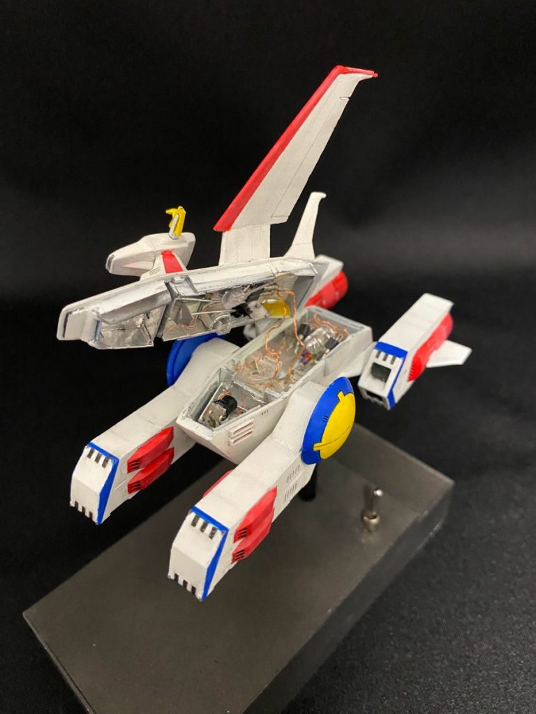 本体は前後２つのブロックに分け、砲弾型LEDをそれぞれ１個配置しています。前方は白色LED、後方は赤色LEDです。主翼の航空灯は点滅しないので、前方のLEDより採光します。後方のLEDは点滅をし、主に左右の格納庫、ミノフスキー粒子発生装置、アンテナとレーダーに光を供給します。【追記】胴体の赤色LEDからの光を、アルミホイルを使って鏡のように２回反射させて艦橋のレーダーに届けてます。意外にうまくいきました。写真には最初の鏡が写っています。光ファイバーの向きが光源と反対方向になってしまうエンジン、主翼、尾翼に対しては、チップ型赤色LEDで補助照明を追加しています。その他、第１艦橋にはチップ型白色LEDを仕込み、胴体部から電源を供給しています。使用LEDの数は、砲弾型２つ、チップ型５つの、計７つです。最後まで見てくださってありがとうございます。ザンジバルの投稿でフォローをしてくださった方もいて、とてもうれしいです。ですが、制作に夢中になってしまったあまり、妻から「当面の間プラモデル禁止」の刑を受けているので、次の投稿はかなり先になってしまいます。どうか今後ともよろしくお願いします。