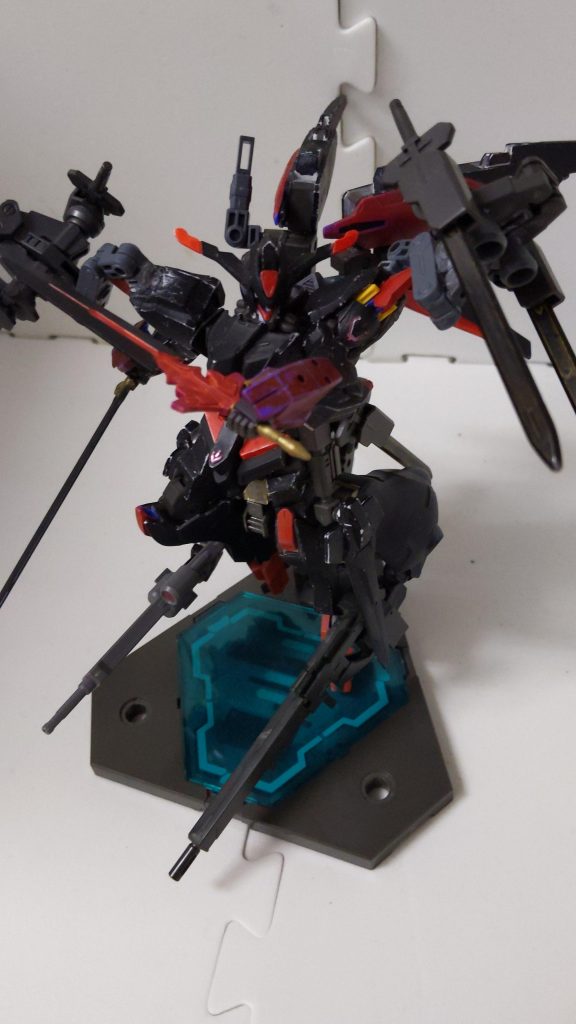 右手の黒い剣が「ノートゥング」、左手の赤と黒の剣が「グラム」です。それと腰部と両肩で合計6本のバエルソードを装備しています。グラムとノートゥングは名前付きですがGBN内での攻撃値はバエルソードと大差ありません。しかしカラスマの厨二心を刺激するからか、「この剣使ってる時の方が撃墜スコアの伸びがいい気がする(本人談)」との事です。