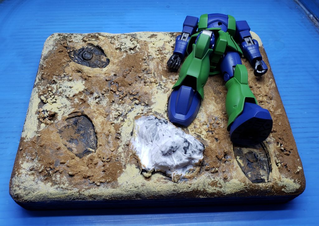 ジオラマベースに主役の頭なしのジャンク品ザクIを配置。この後ダメージ加工するんだけど、一応合わせ目消して全塗装してあります。