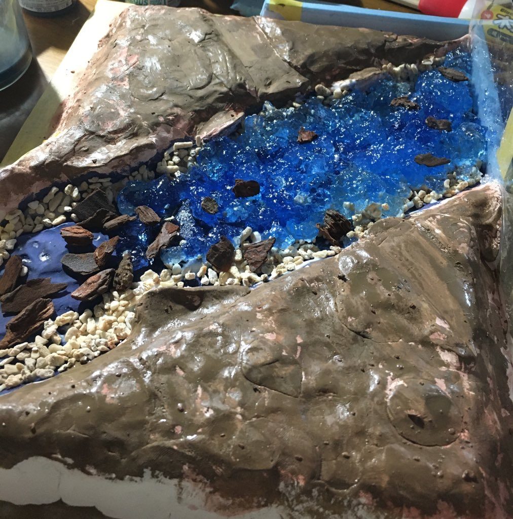 ジオラマで川を表現してみたいと思っていたのですがレジンだとお財布に優しくない（お小遣いが少ないので…）ということで今回はセリアのキャンドルゼリーを採用。ゼリーの下は暗めの青で塗装しその上に石などを撒きました。ゼリーには緑系混ぜるといいのかな？と思いました（今回は青系の塗料をゼリーに混ぜました。）雪は木工用ボンドと水を1:2、それに対して重曹を1混ぜてドロドロにしたもので表現しました。木は銅線を五本まとめて棒状にしたものにグリーンモス（ダイソーで売ってるやつ）をボンドを使いながら盛る感じで作成しました。（失敗は否めない）ジオラマ自体は100円ショップだけの道具と材料で作っているのでやってみたい方は是非やってみてはどうでしょうか？