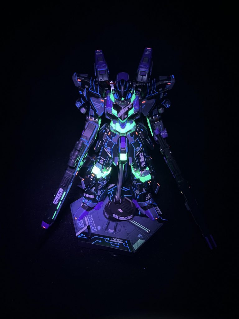 サイバーパンクとして意識したもの④「発光」今回のメインテーマでした。サイバーパンクといったらネオンだろうということで、蛍光エナメルを使用しての墨入れに挑戦しました。いつもは影になるところを発光させるということでスジ彫りはいつもより慎重に行いました。(それでもまだまだ甘いところはたくさんあったのですが、それは見てるみなさんには見つからないよう祈っております笑)単色ではつまらないので、レッドチップの代わりに蛍光ピンク、パーツの蛍光グリーンと合わせてブラックライトが当たった時に三色が発光する様にしました。