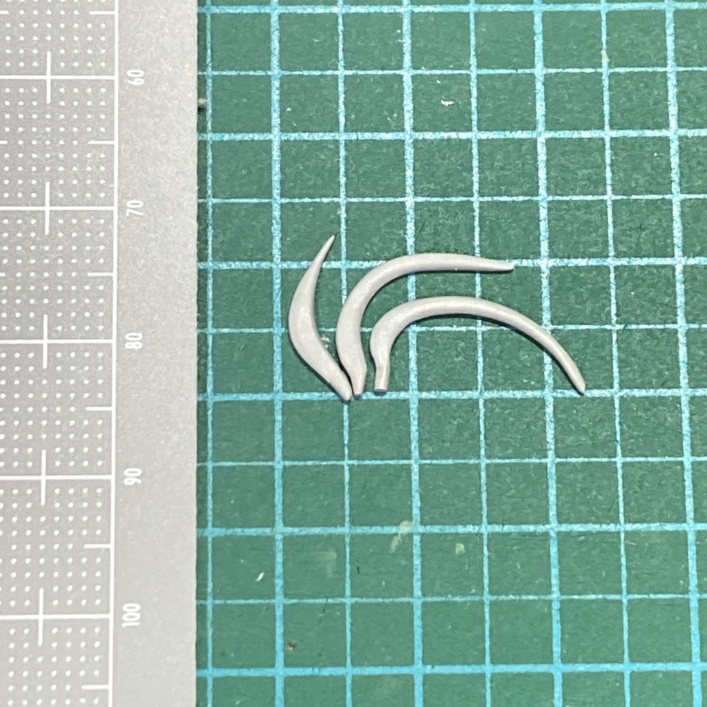 初期段階では頭に刺したブーメランをアホ毛に見立てたのですが、サイズ感、デザインも台無しなので、グレーのアホ毛をブーメランに見立てる方向に変更しました。1mmプラ板からの削り出しです。