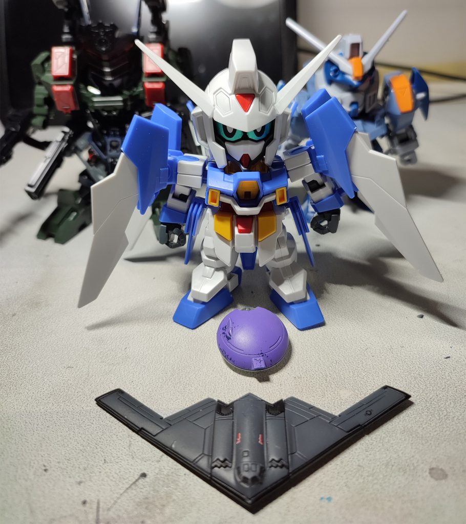 着想からキット集めを開始し、ざっくり素材を配置したところ。AGE-2、サージェントヴェルデバスター、ブルデュエルなどを混ぜれば上手くいくかな、と。特徴的なヘッドに関してはグリモアの頭部と食玩おまけのステルス機(中古ジャンクで入手)をくっつければ何とかなる、とこれまた甘い幻想を抱いてました。このときは…(いつものパターン)