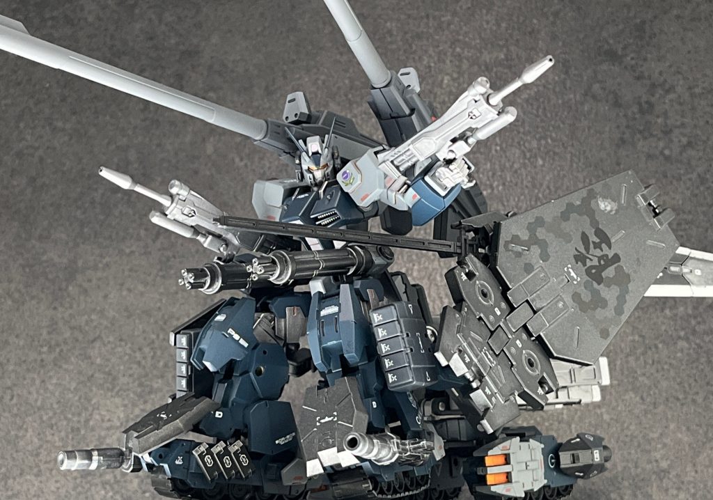 ・GTM-G02 5連装ミサイルポッド　前脚部に設置されている5連装ミサイル。主に建設作業で岩盤等を破壊するために開発されたもので、MSにも一定の効果を発揮する。・MMO3-B04/C 短射程ビームガン　MMO3社が開発したビーム兵器の一種で、射程は短いもののある程度の連射が可能で主に対戦車対歩兵用とし運用される。・MMO3-GG033X ビームガトリング　MMO3社が開発した宇宙デブリ迎撃用のガトリングユニット。そもそもは人工衛星やコロニー防衛用に売り出していたものを、MS用に転換し本機の両腰部に搭載している。・MMO3-MS002a-R フレキシブルアイアンシールド(ラミネート加工)　クローラーユニットの両サイドに設置された、アンチビームアンチマテリアル装甲。専用アームで接続されているため、ある程度自由に可動して、敵のビーム攻撃や実弾攻撃を防ぐほか体当たりにも使用できる。・175mmグレネードランチャー装備57mm高エネルギービームライフル　両手に1丁ずつ装備したビームライフル。デュエルやストライクノワールが使用したものと同一で、アクタイオンプロジェクトで生産されたものを横流ししている。専用ラックがないため、実体剣(イガリマ)使用時は投げ棄てなければならない。