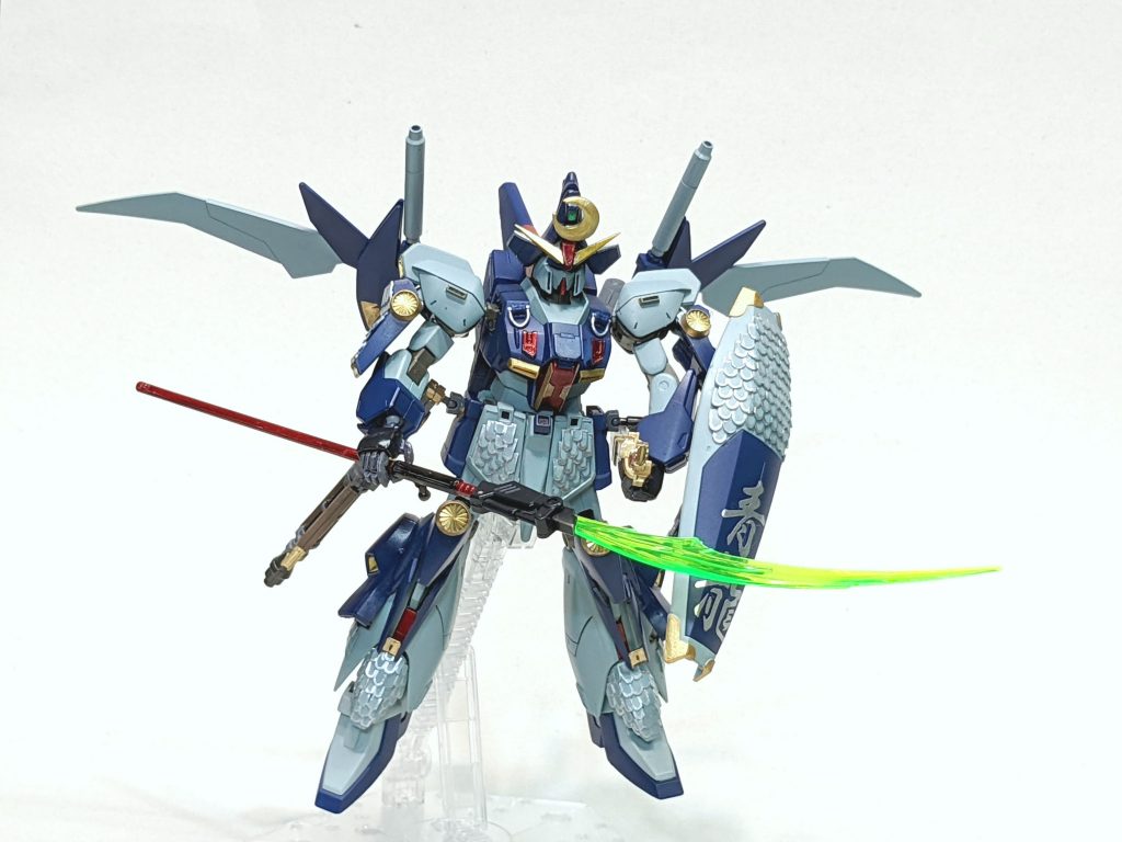 ・武装設定では薙刀(なぎなた)とバルカンのみ。薙刀はガンダムデスサイズの鎌を立てた状態。これだけでは武装があまりに少ないので、独自解釈でライフルも別で製作。30MMの武器を使用し、種子島風ライフルに。刀もビルダーズHDを使用。しかし基部が簡単に壊れたので、ボールデンジョイントの小さいやつをくっつけて脇楯に取付できるようにしました。腕部グレネードはそのまま。ウイングバインダーにジャンク部品のライトニングバックウェッポンシステムのビームキャノン部分を基部毎移植。ただし、ビームサーベルとして機能できるように分離、させ、一応専用のビーム刃がつけれるように加工。ハイパービームサーベル兼ビームキャノンとしました。シールドはノーマルに鱗加工。青龍の文字は銀色であったことと、当方の筆文字は下手なので、早々に断念。文字ステッカー製作業者にネットで発注し貼り付け。ということで薙刀(ビームナギナタ)×1、刀×1、ハイパービームサーベル兼ビームキャノン×2、種子島ライフル×1、腕部グレネード×2、バルカン×2。