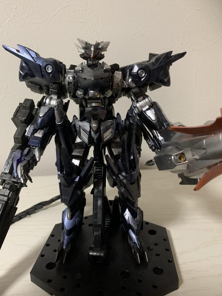 正面。一見するとガンダムに見えないが、頭部には各種センサーを強化するまるで鴉を模した様なセンサーマスクを装備。機体の各所には、莫大な余剰粒子を機体周辺に散布し、不可視の防御フィールドを形成するGNプライマル・アーマー兼、一基で機体全体を覆うGNフィールド展開可能な整波装置を装備している。(閃光がアサルト・アーマー使用時に展開していた部分です)