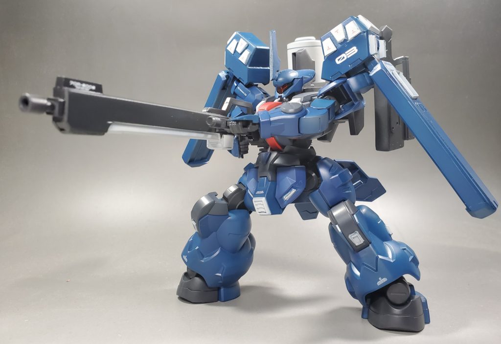 主兵装のマシンガ。実弾を安定した高速連射できるよう大型化している。フォアグリップがあり使用することにより安定した射撃をおこなえる。銃後部からベルトリンクによりパックのマガジンドラムに接続されており、自動装填により絶え間ない射撃をおこなう。