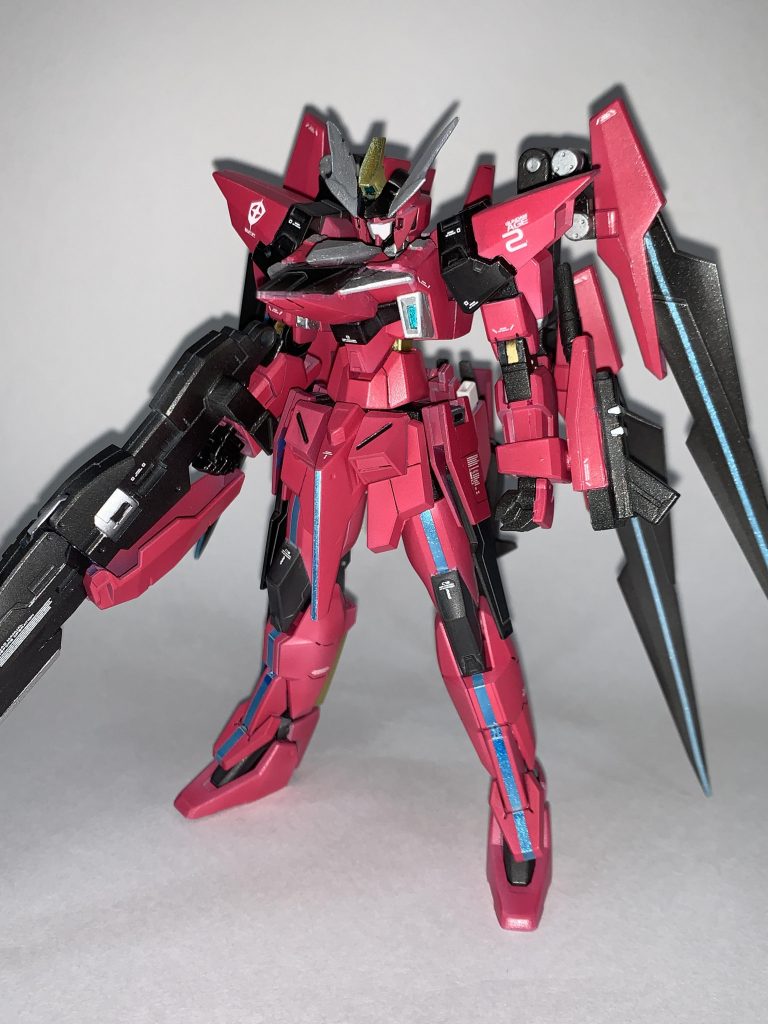 ガンダムAGE-2 2号機コード「エクセリオン」AGE-2の量産化を目的に、データ取り、及びアグレッサーの目的も兼ねて制作された機体。本機の制作には連邦だけでなく、マッドーナ工房も招集されている。本機の製造はまず、オリジナルと同等のAGE2を制作するところから始まり、技術的困難を極める部分、テストパイロットからの意見を元に扱いやすさを改善していく方向で開発が進められていた。AGE2の特徴である肩部ウイングユニットは制作が困難なだけでなく、テストパイロットからは扱いづらさの声が多数上がっていた。そのためバックパックに集約、更にはヴェイガン側の技術である光波推進技術を取り入れることで解決している。胸部ユニットは、開発スタッフの1人が「この機体、積極的な可変運用が前提なのにライフル壊れたら変形できなくないですか?」と言ったのをきっかけに増加装甲兼機首パーツとして追加された。結果としてハイパードッズライフルが破壊されても本体バランスを崩さず、変形運用が可能となった。本機はデータ収集後、運用データをフィードバックした次世代可変量産機のテストベッドとなると同時に、AGE2の延命効果が期待されていた。しかし、オリジナルのAGE2が任務中に消失してしまったため、延命を口実にした高コストの可変量産機を制作する意味がなくなってしまい、可変量産機プロジェクトはプロトクランシェに譲ることとなってしまった。一機のみ製造されていた本気は、その後地球進行したヴェイガン戦に駆り出されることとなる。と言ったことを妄想しつつ制作しました。