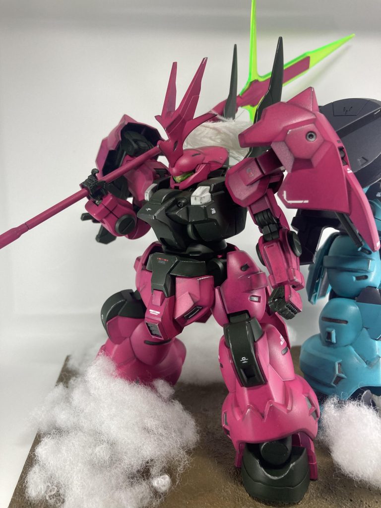 グエル専用機はチェリーピンク(ボディ)、ダークグリーン(関節など)で塗装しました。チェリーピンクはポリカーボネート用スプレーを使用しましたが、問題なく定着してくれました。また、ダクトなど一部はガンメタル(エナメル)の部分塗装し、ウェザリングカラーでウォッシング、ウェザリングマスターやドライブラシで汚しを加えております。羽根飾りは100均のクリスマス飾りを切り取って使用しています。