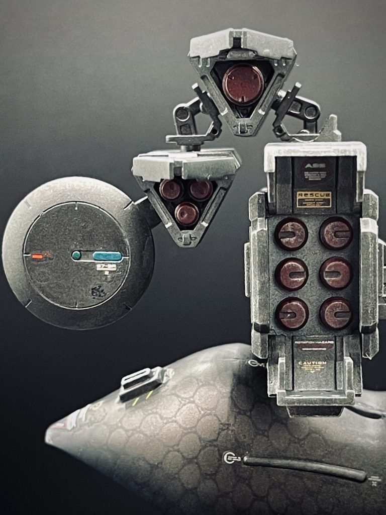 右ショルダーの武器パーツ正面。色味はハイゴッグ本体のカラーリングと整合を取りながら暗いトーンで調色し、塗装後、軽く金属調のダメ処理を加えました。