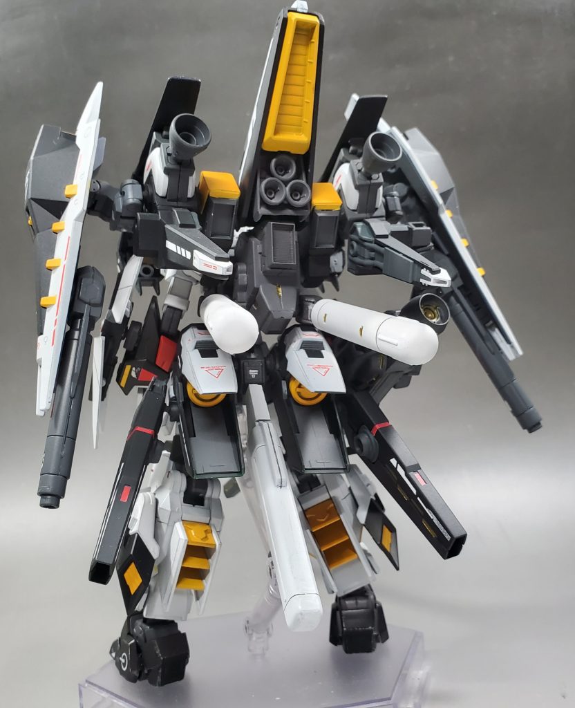 背部。大型スラスター、ミサイルコンテナ内臓のブースター、それに接続されているシールド、ブースター、キャノンの複合兵装。腰部には大型ブースターとそれに接続されたビームキャノン、プロペラントタンクを装備しています。