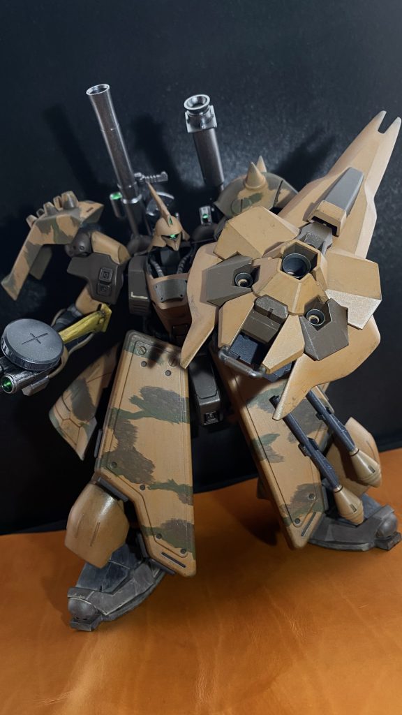 　「奴ら、俺達の基地を狙ってるんじゃないのか」　近くに来たランドルが言う。違う。俺達の基地が狙いなら、あんな重装備のMSをよこすより爆撃機で爆撃した方が早い。そんなことは、トリントンの連中なら知っている。それに、あの機体はトリントン基地の所属じゃない。あのホバートラック、積まれているのは、弾薬を始め、MSに対する補充物資ばかりだ。つまり連中は、なんらかの理由があって、MSで北上している。だが、俺はあの連中に渓谷内を通って欲しくない。「俺が、台地の上に上がる道の手前で狙撃する。連中、相手が一機なら追撃してくる筈だ。もし俺を無視して渓谷側に行ったら上から狙撃して足止めしろ。俺が後ろから挟撃する」　一機で大丈夫か。そう言うマーカスの声に、言う。大丈夫だ。単騎だからこそ大丈夫なんだ。と、複数機同士の交戦は、戦闘を行う範囲が広くなる。連中にとって複数対一という状況を作り、俺がこの台地の上で戦い、渓谷の方から離れるように動けば、渓谷側の被害は無くなる。「連中が台地に上がって来たら、お前達は「静か」に基地に戻って、「静か」に警護だ。気取られるなよ」　了解。「静か」に、ですね。二人の声が重なる。ご武運を、と言う声を聞きながら、巨人となった自分自身である、量産型サザビーを疾らせる。左腕のウェポンシステムをON、接続された大型のシールド、それに内蔵されたメガ粒子砲のチャージを開始する。この機体の最大火力を誇る武装だ。なんでも「袖付き」と呼ばれた残党組織の首魁が乗る機体の専用装備として試作されたものの、でかい、重い、当たらない。と言う涙が出るくらい素晴らしい武器だ。　メガ粒子砲のチャージが丁度終わるタイミングで、狙撃地点に、連中はまだこちらに気付いていないようだ。いや、気付いてはいるだろう。だが、攻撃ポイントついたのはこっち先だ。正面。やらせてもらう。　ターゲットサイトを先頭のジェガンに合わせ、トリガーを引く。