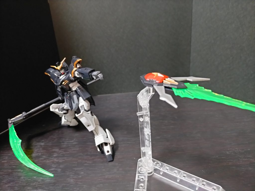 ビームサイズ:本機の主兵装である鎌状の高出力ビーム刃を発振する近接兵装。発振器の角度を変えることで槍のようにも使用可能。ビームサーベルより広い間合いと攻撃範囲を有しており、一薙ぎで複数の敵機を撃破する威力を持つ。また、ウイングガンダムのビームサーベルと同様に水中での使用も可能としている。非使用時には柄が短縮化され、リアアーマーのラックにマウントされる。バスターシールド:腕部に装着されるガンダニュウム合金製のシールド。シールド先端部にビーム発振器が内蔵されており、側面のブレードを展開すると共にビーム刃を発振することで近接兵装として機能する。また、シールド後部にはスラスターが内蔵されており、高速回転させながら射出することで中距離の敵機にも対応可能となっている。