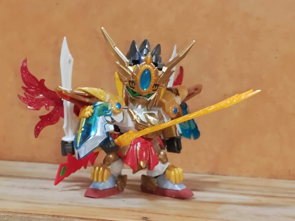 アカツキモチーフの武者となります。（ライオンと虎とで違いますが）神獣のモチーフがネコ科繋がりの赤流火穏（日本語公用の国のMSなのに…）の武人として作るため、轟の機体をメインに使用しています。楽轟はその名の通りラゴゥをモチーフの1つに入れています。因みにライガーと呼ばれる虎とライオンの交配種が存在するとのことです。頭部：曹丕に馬超ブルーのメインカメラと髪（写真はありませんがアカツキのモールド入れてます）。カブト飾りは周愉ヒャクシキメインに同アカツキ、陸遜で構成。因みに当初は陸遜の兜をそのまま使う事も考えてました。胴体：轟大帝にアカツキ。腕：三国伝系の肩（どれだったっけ…）に三位一体の腕。鎧は孫権と猛虎装、アカツキの組み合わせ、腕甲はヒャクシキ。旺舞の装のクリアパーツは孫権そのまんま。下半身：腰は姜維にアカツキ、膝は黄忠とアカツキの組み合わせ、足はヒャクシキに猛虎装とアカツキ貼り付けただけ。バックパック：劉備に猛獲、姜維、ボールデン、ハリマオの組み合わせ。刀は黄忠から。阿修波刀：陸遜（実は蒼波の余り）に虎テイ刀を貼り付けただけ。楽轟：夏侯兄弟に轟大帝、張郃などジャンクの組み合わせ。実はハリマオなどを使った小さい物にする予定でしたが可動するモデルにしたかったのと、龍輝宝や（インフィニットジャスティスガンダムモチーフの）大将軍の相方（鳥モチーフ）と併せるためイチから作り直しました。