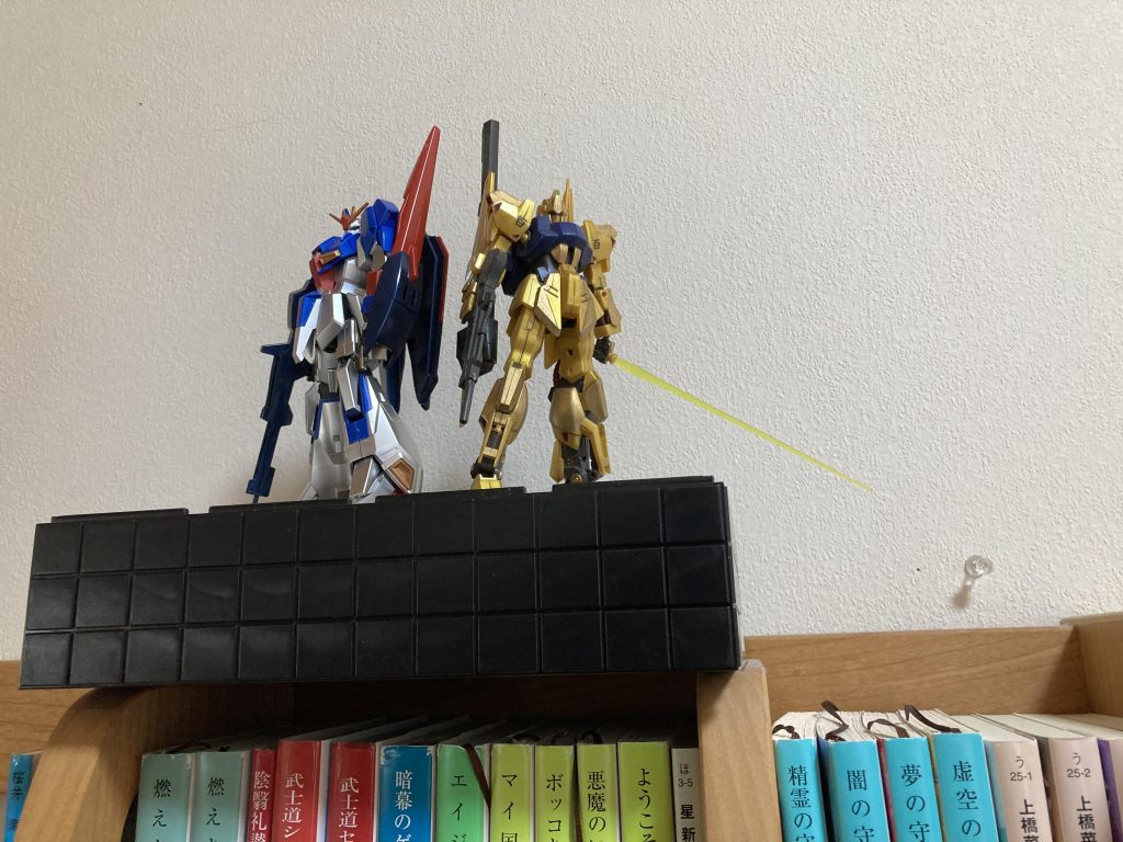 年末の大掃除でガンプラ飾る棚がいっぱいいっぱいになってあぶれてしまったので本棚の上に飾りました。両方輝いていてかっこいい。下からその勇姿を拝んでます。